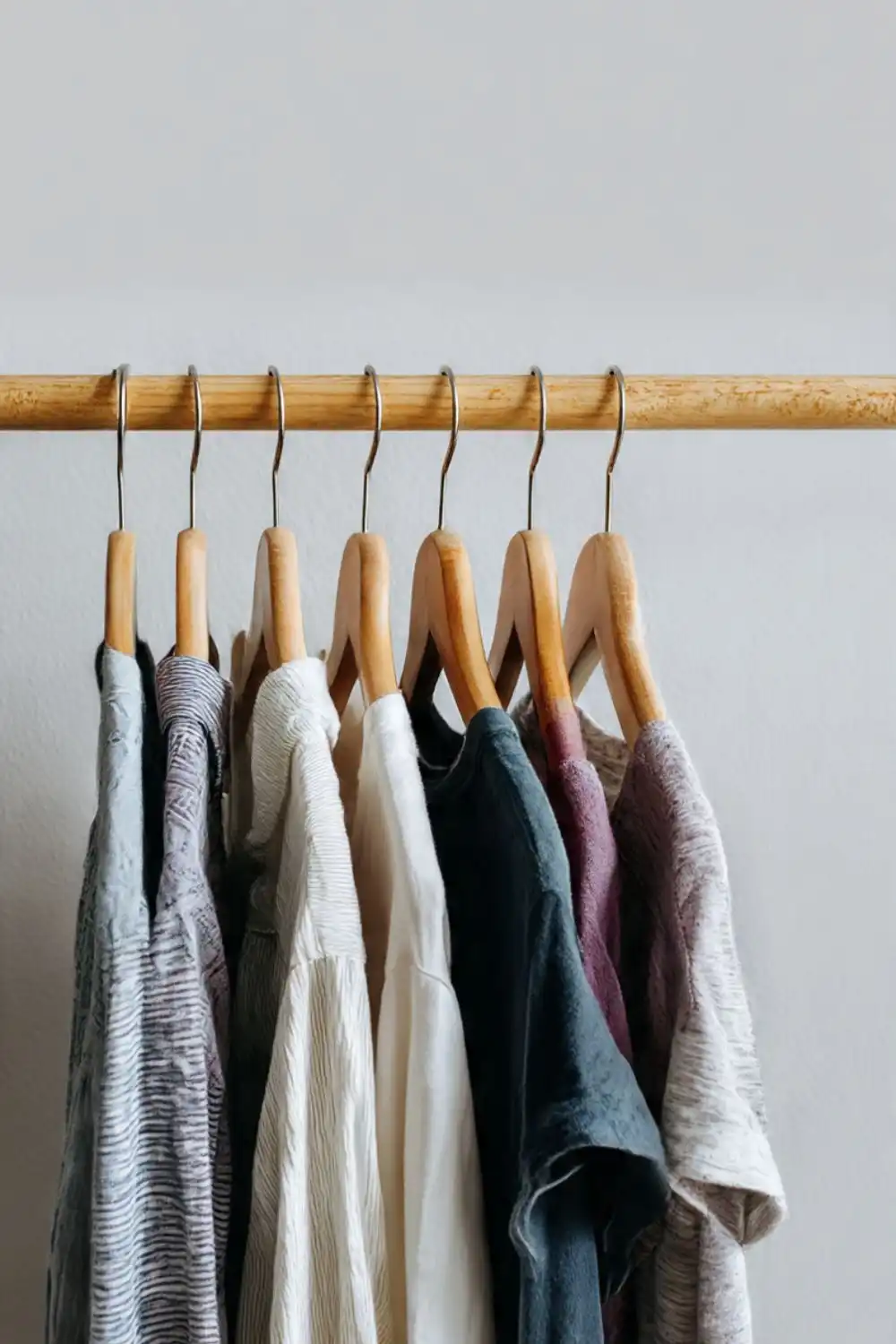 Various shirts on wooden hangers in closet.