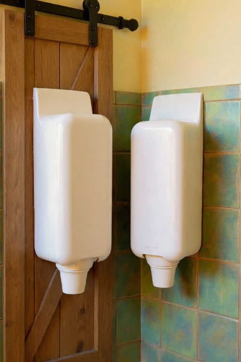 Unique tall urinals in rustic bathroom setting.