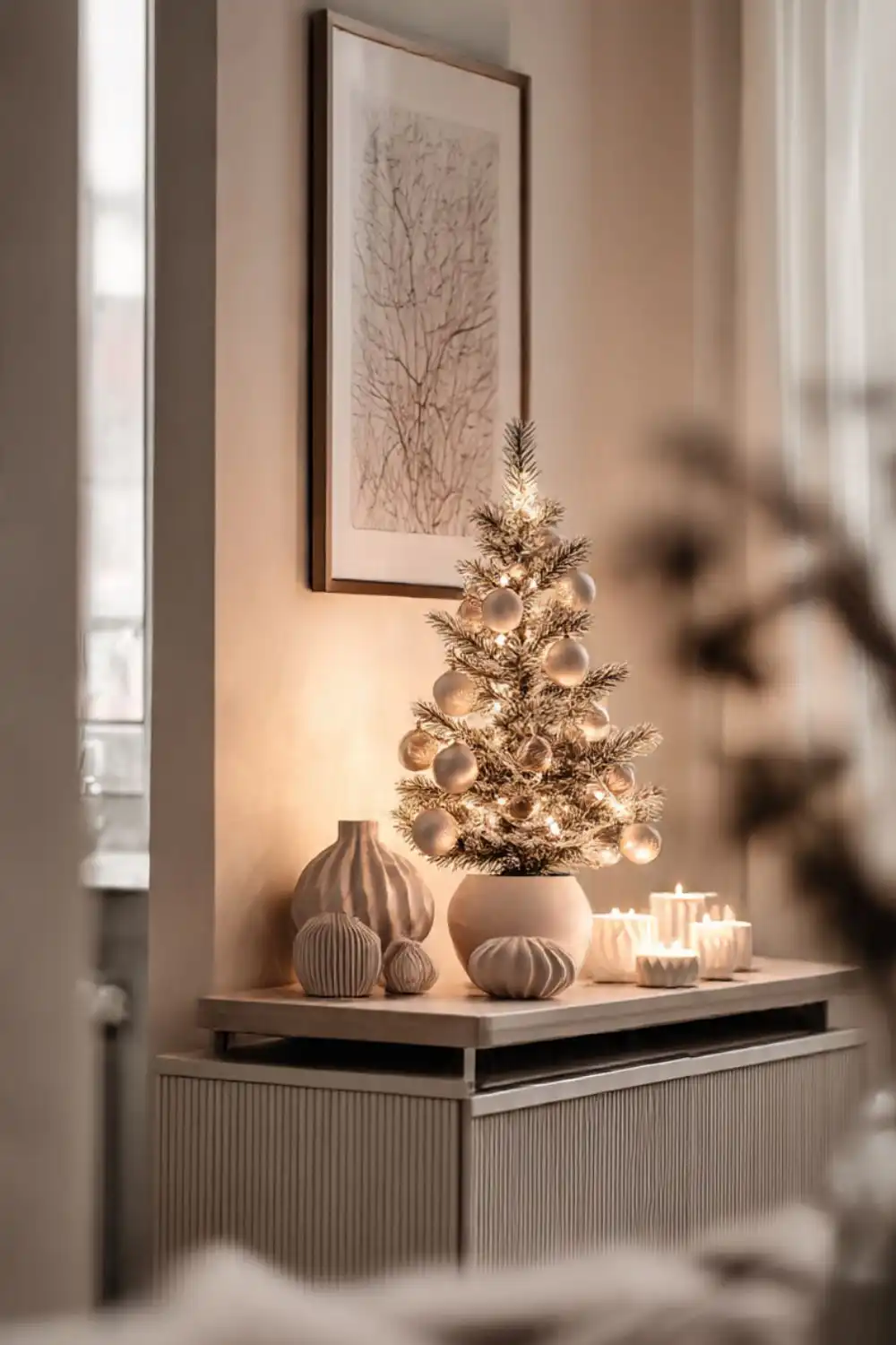 Small Christmas tree with lights and candles on table.
